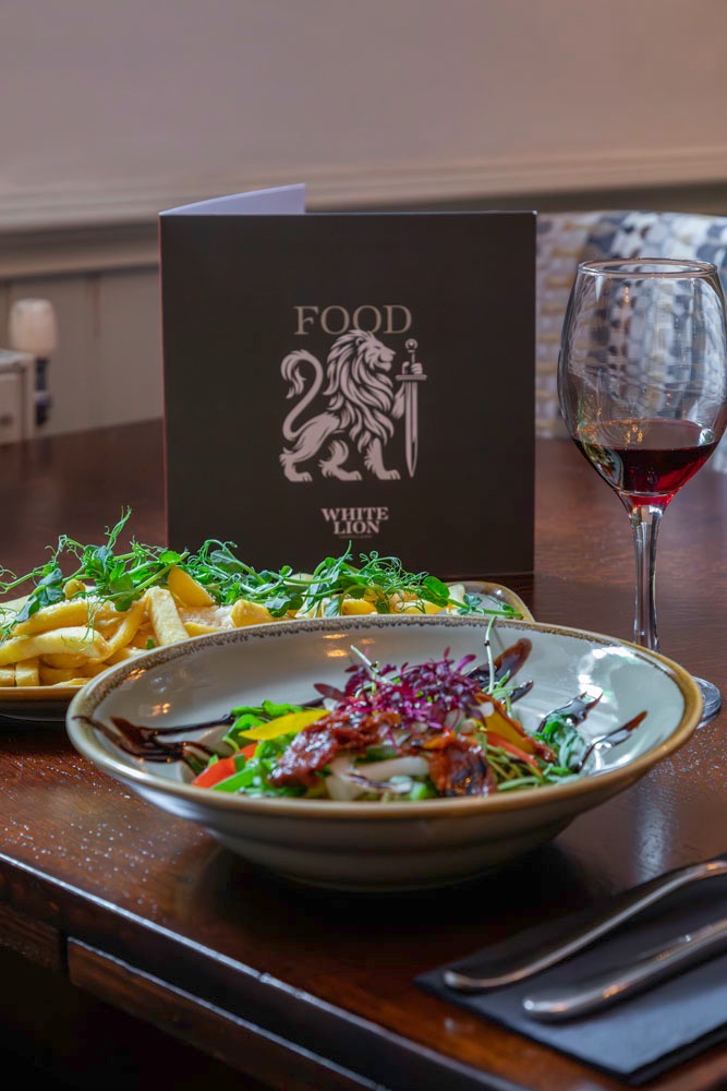 Food and a glass of red wine served at The White Lion, Upholland
